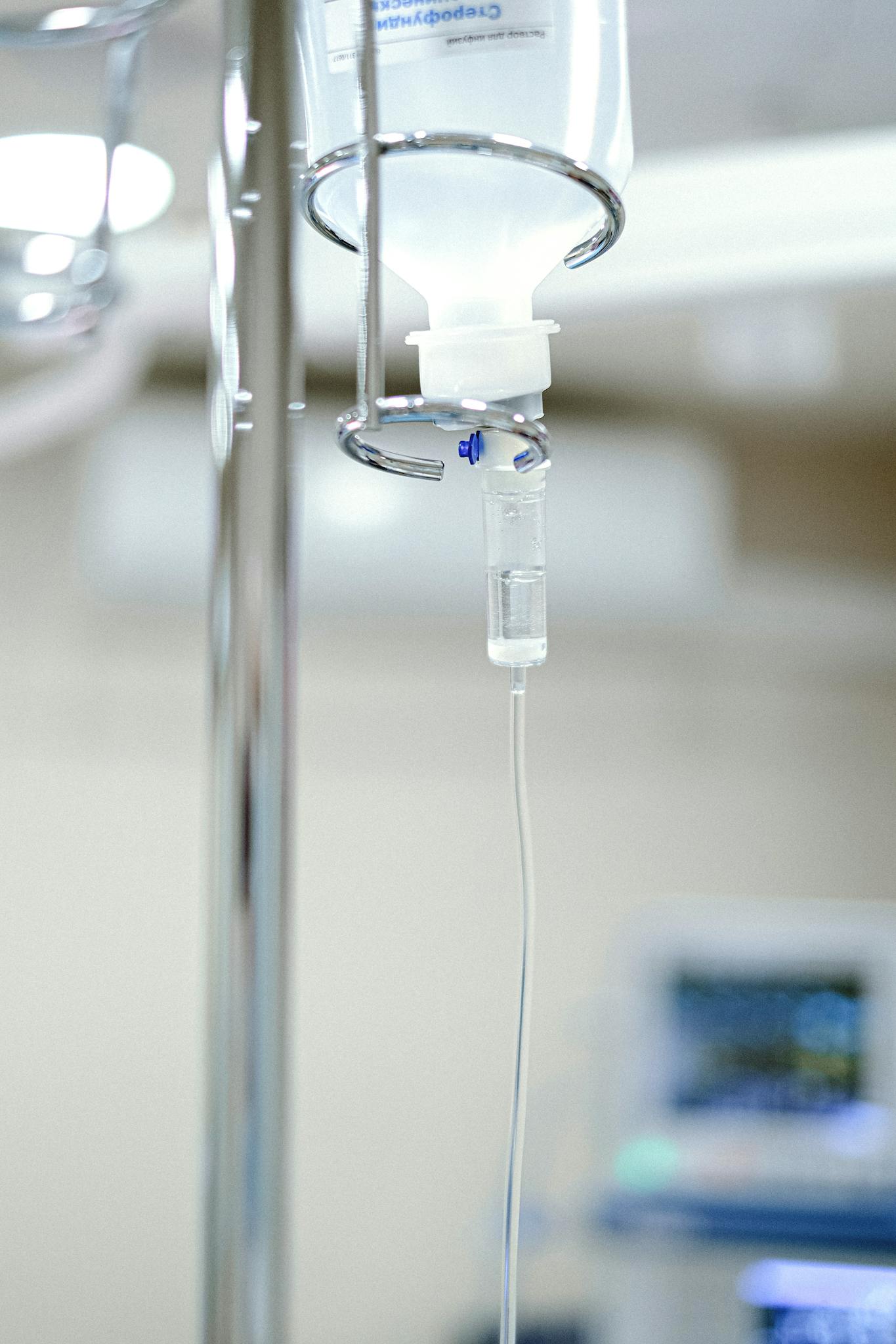 Close-up view of an IV drip chamber and stand in a clinical hospital environment.